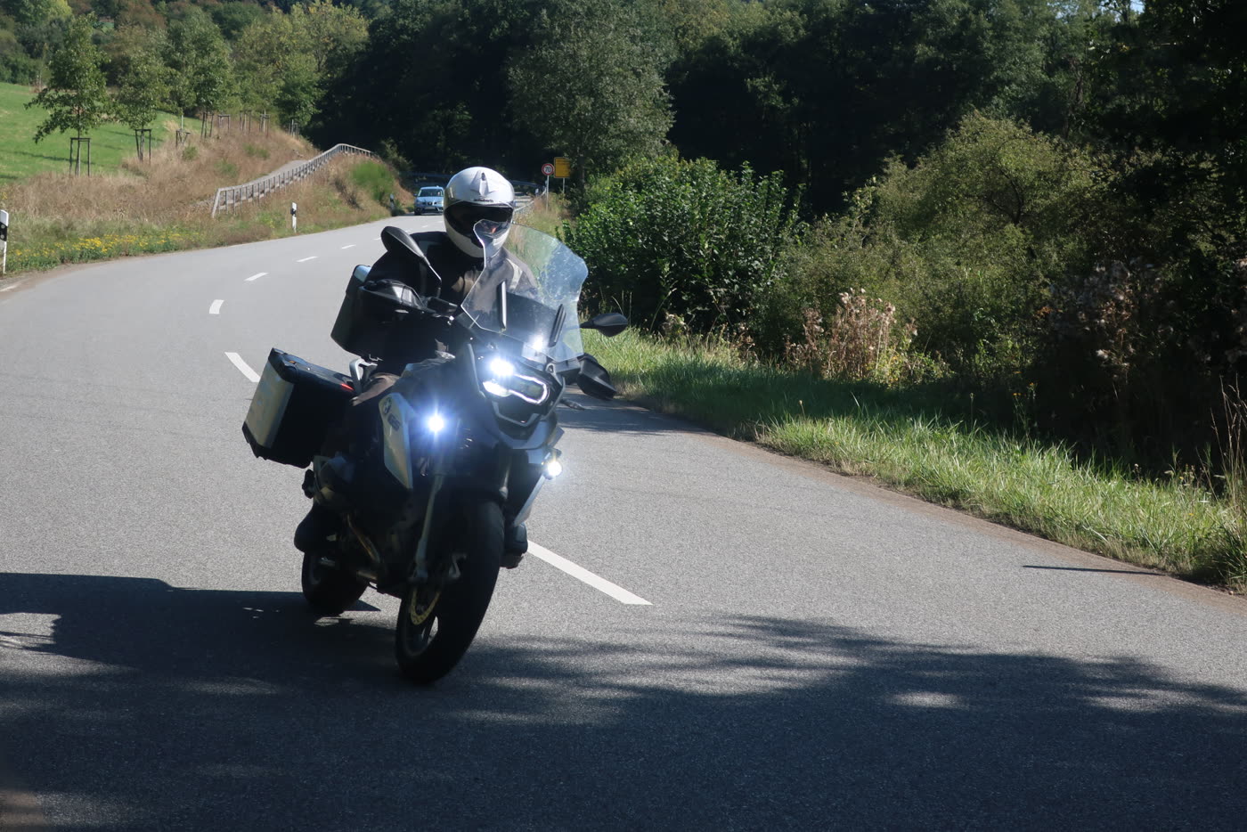 Motorrad auf einer sonnigen Landstraße zwischen Wiesen und Wald Motorrad auf einer sonnigen Landstraße zwischen Wiesen und Wald